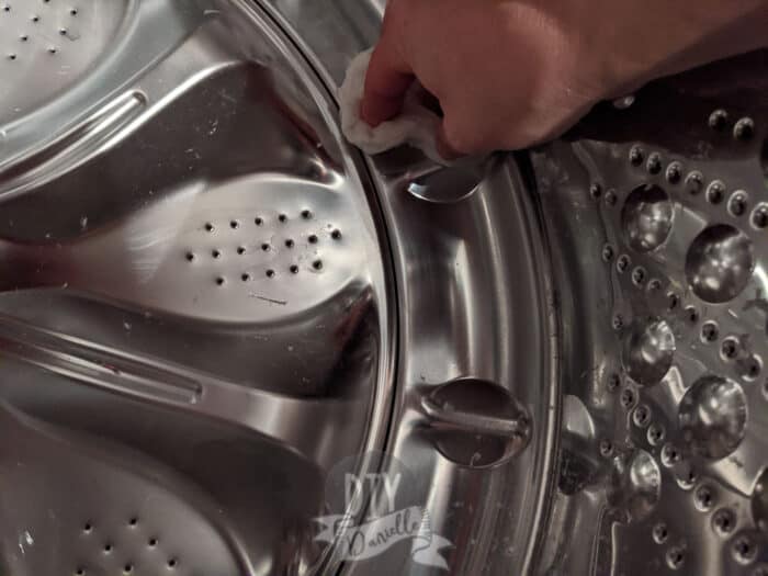 Wiping down the inside of the washing machine with a wet towel.