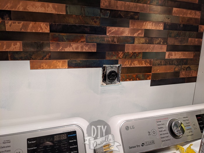 metal tile on wall behind washer and dryer