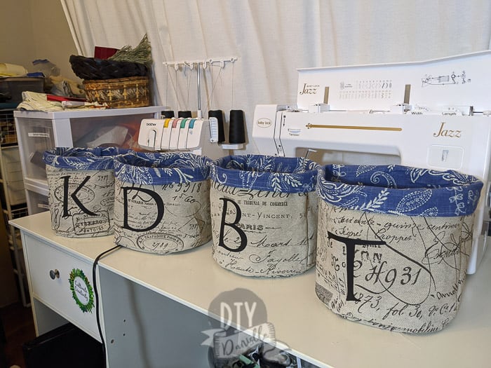 Two layer reversible fabric baskets in front of my sewing machines. Each one has a letter for the person who has the bin!