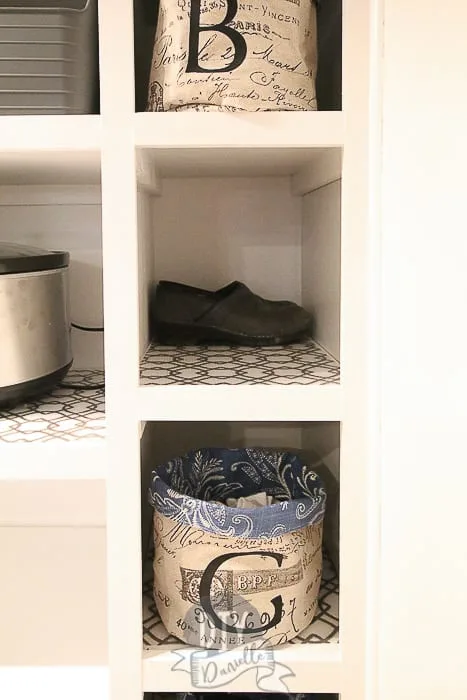 Shoe storage for the mudroom shelf. The baskets hold socks and have a letter for each person's first name. Shoes hide behind the basket.