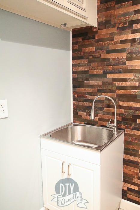 Small laundry sink to replace the large one in the laundry room before. Aspect Backsplash in Metal and Aged Copper behind the sink.