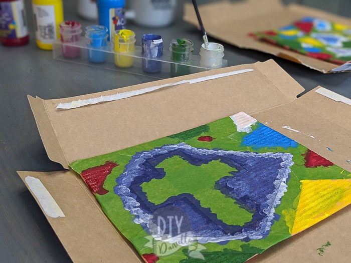 Painting a cellulose dishcloth that was taped for a stainglass look. Cross in middle.