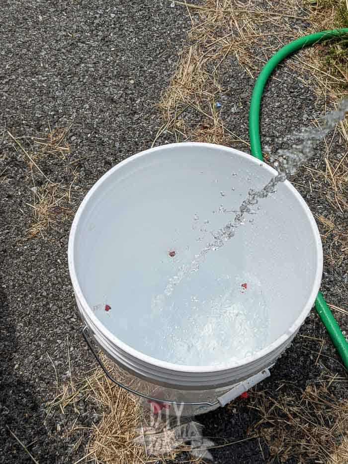 Filling a 5 gallon bucket turned into a chicken waterer with water