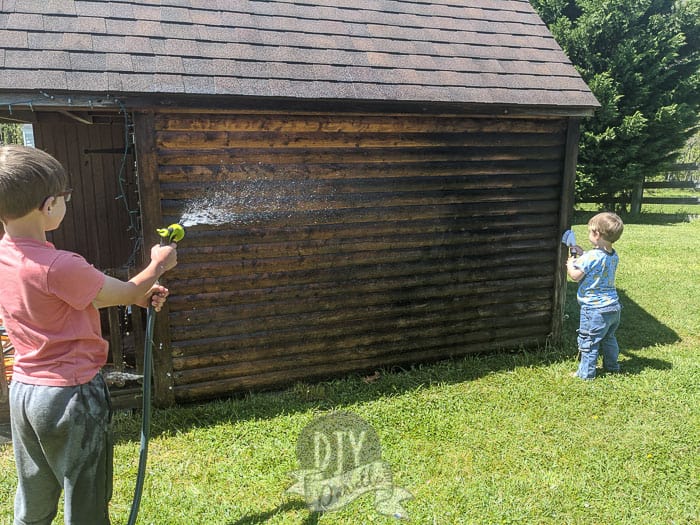 Kids helping clean the old wood log cabin.