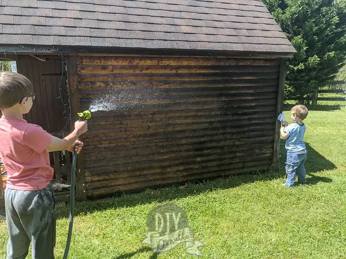 Kids helping clean the old wood log cabin.