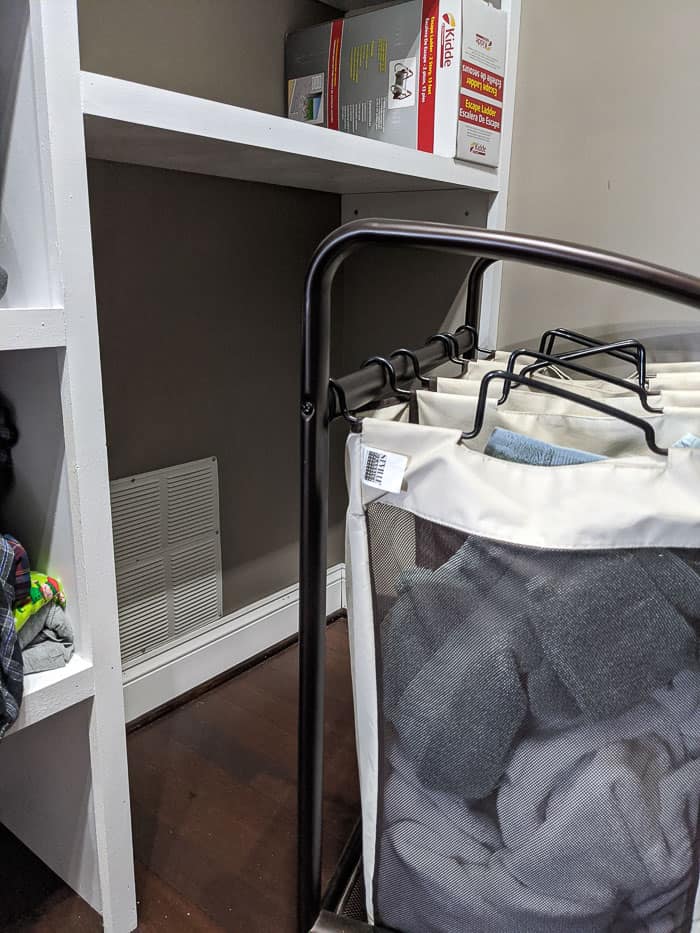 Rolling laundry bin organizer under the custom closet shelf designed to fit it. You can see the vent behind it that we didn't want to block with a shelf.