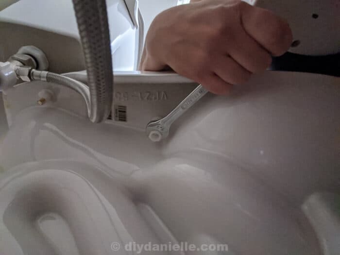 Tightening the plastic nut that the plastic screw goes into to hold the toilet seat in place.