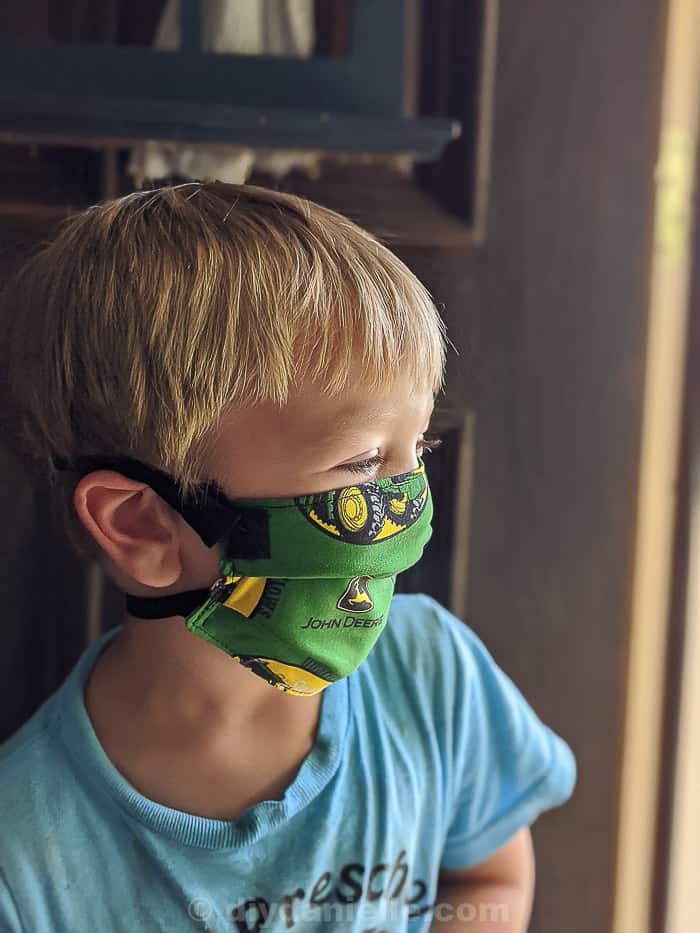 3 year old boy with blond hair wearing a John Deere mask with Velcro straps,