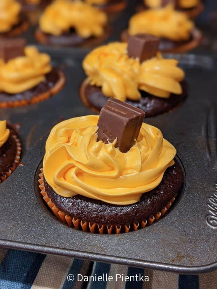 Kit kat pumpkin stem on a chocolate cupcake with orange frosting.