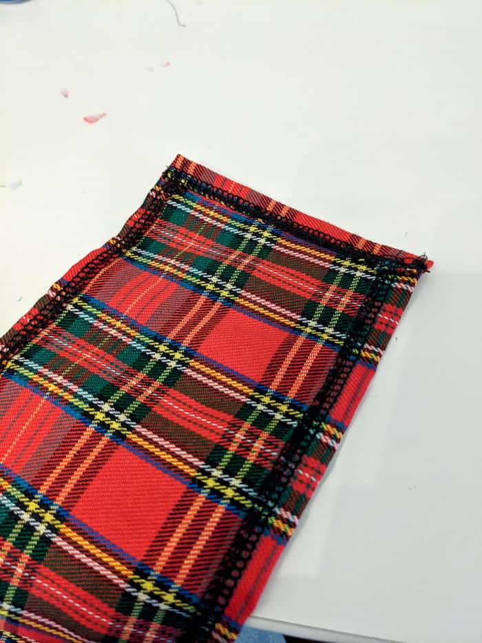 Piece of plaid fabric hemmed on three sides.