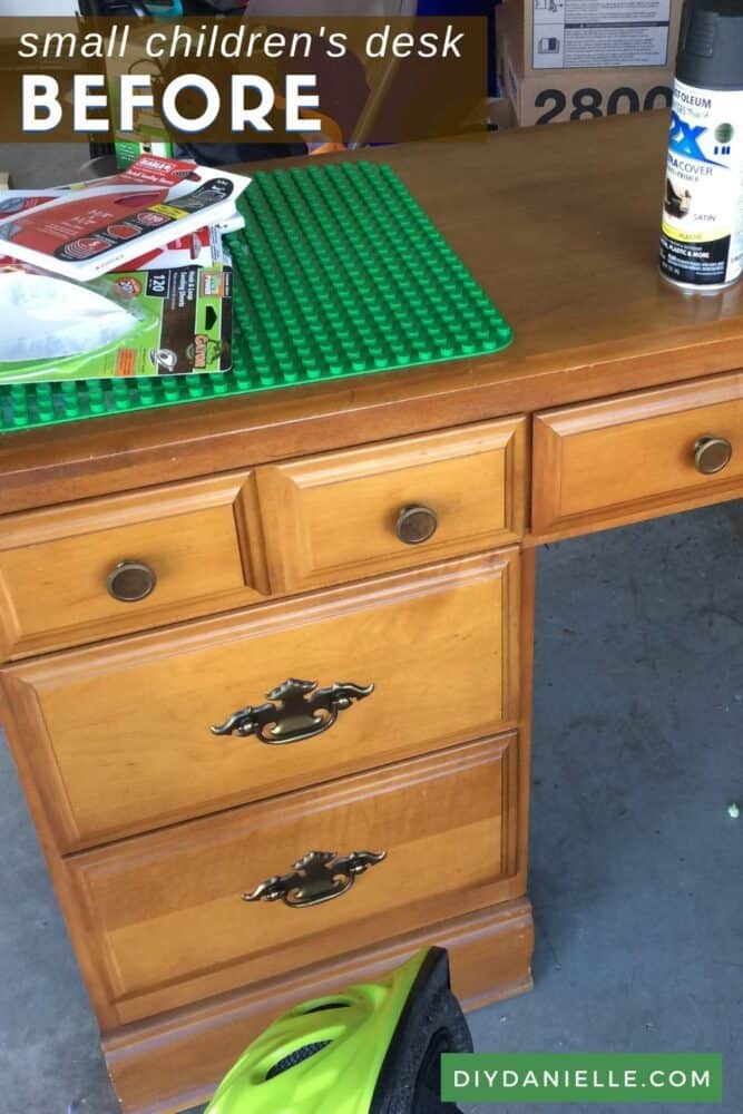 Before picture of a small desk that I converted into a Lego desk, then a small computer desk. On top of the light brown desk is paint, sanding paper, and a lego plate.