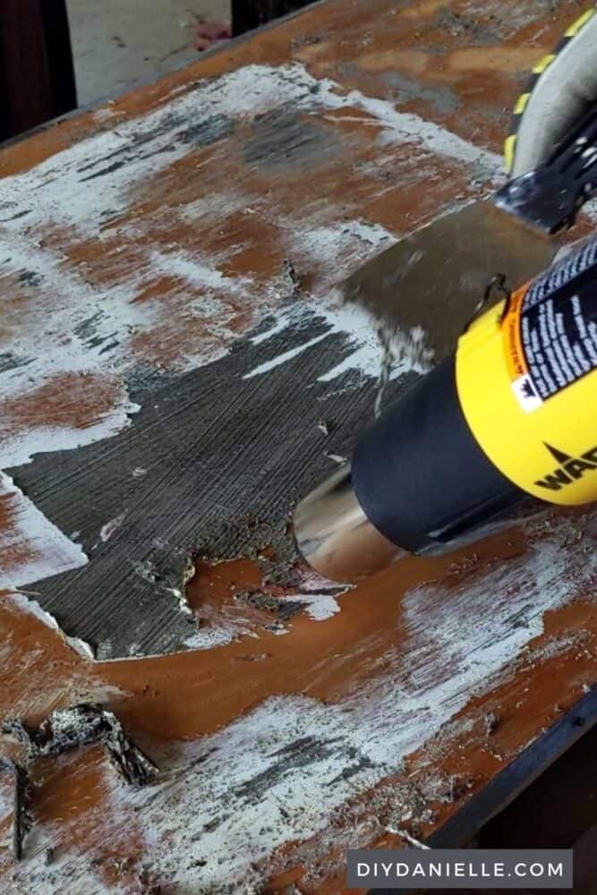 Using a heat gun and scraper to remove paint from the top of this desk.