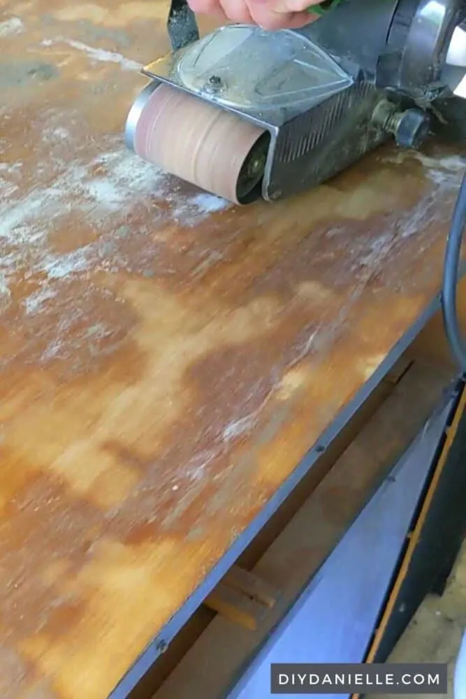 Using a belt sander to finish sanding the top of the desk.