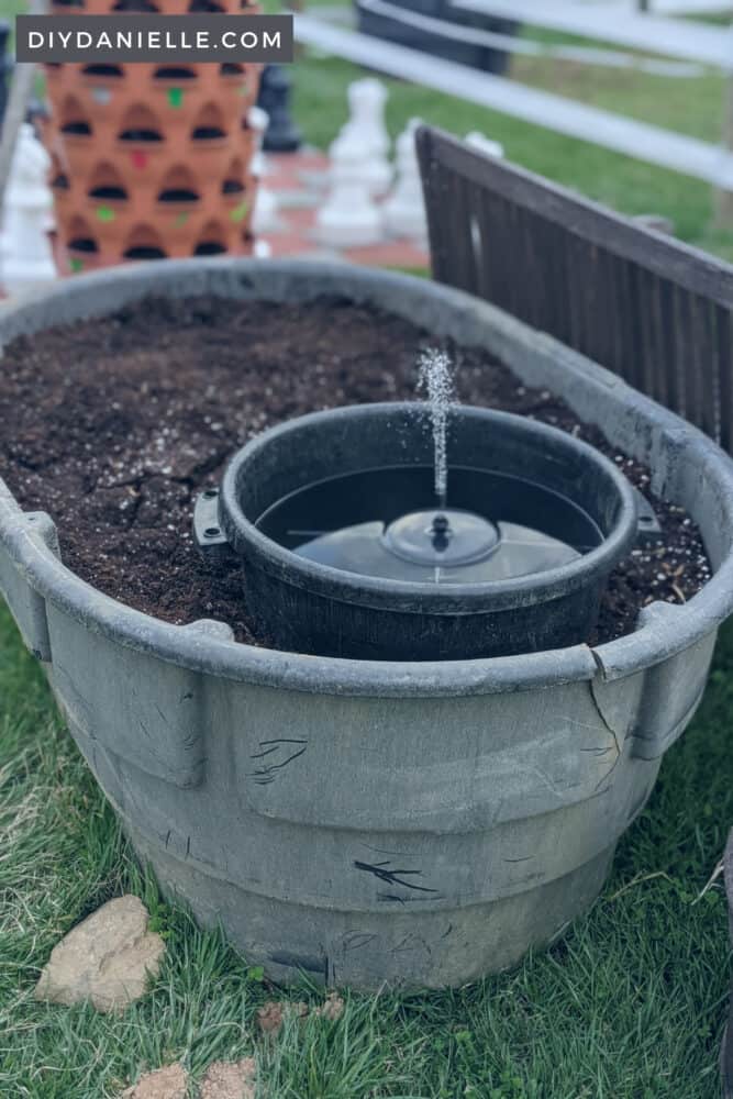 DIY Trough Planter made from a cracked horse trough. I added a smaller muck bucket inside, filled it with water and a solar pump to create a mini pond inside the planter!
