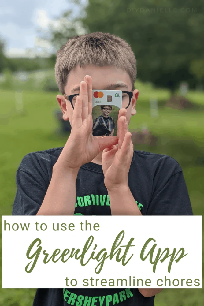 How to use the Greenlight app to help streamline chores. Photo of a 9 year old boy with blond/light brown hair holding a photo debit card from Greenlight. The card has a picture of him holding his pet chicken. 