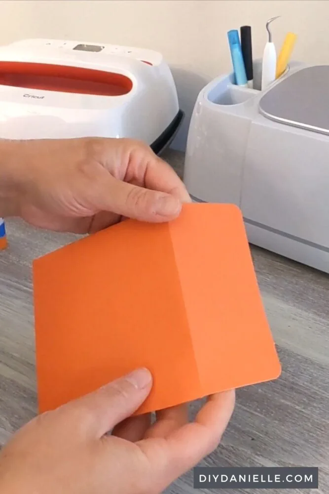 Folding an orange greeting card envelope that I made with cardstock on my Cricut Maker.