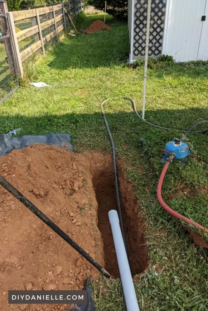 Photo of boring setup for running electric underground. You can see the smaller trenches dug in each corner... they need to be big enough to fit the pieces of conduit. The machine on the right provides pressure (and a lot of noise) to help send the machine digging like a groundhog under the soil.