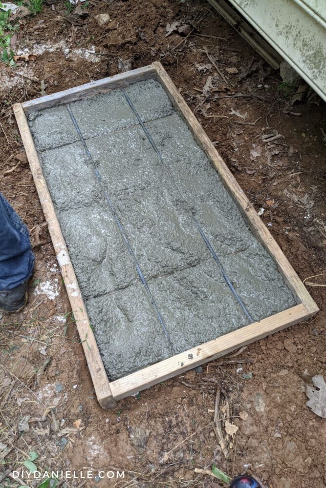 Rebar added to the concrete. Three shorter pieces are spaced out with two longer pieces on top, perpendicular to the short pieces.