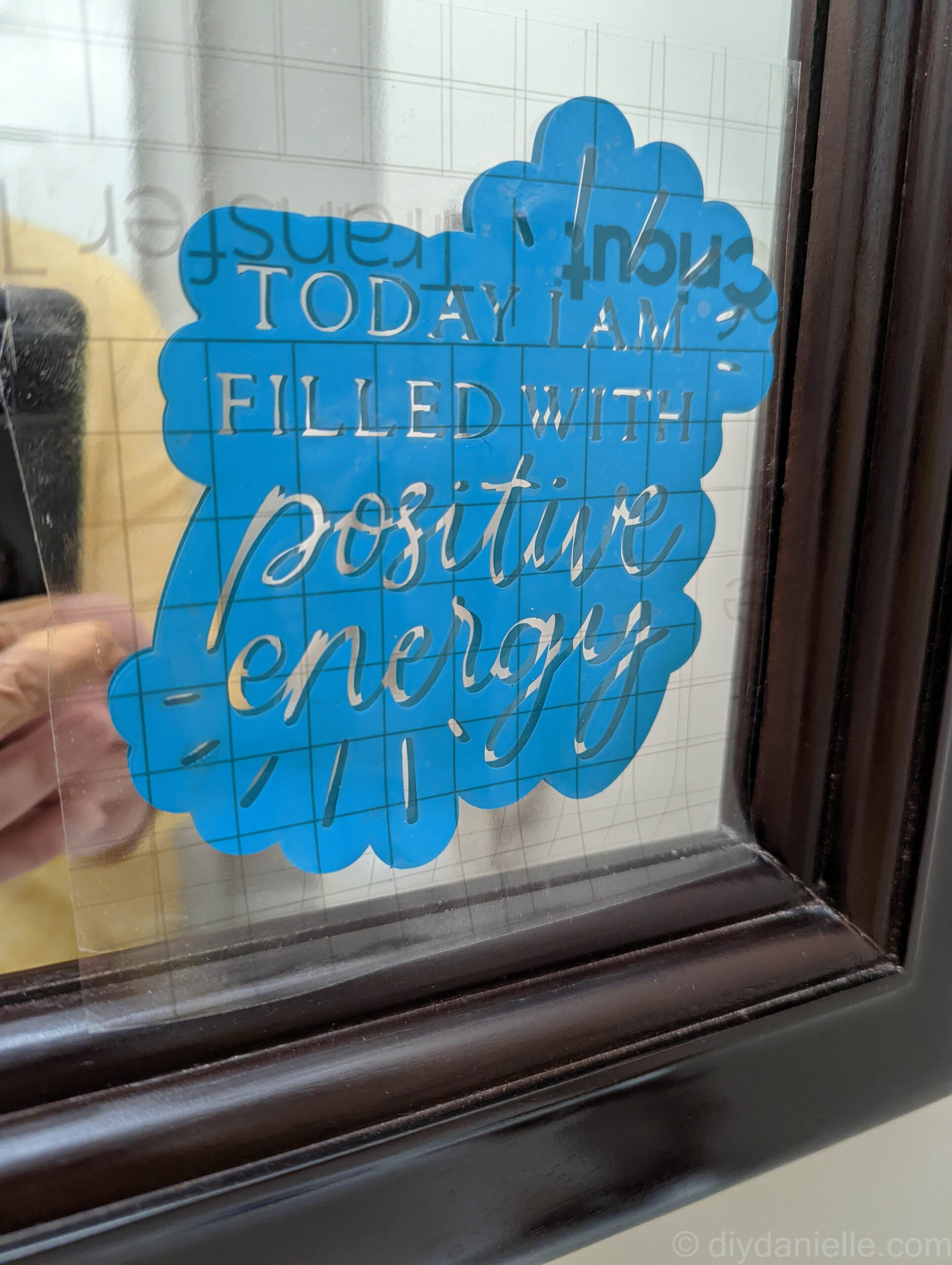 Vinyl decal on a mirror with transfer paper still attached.