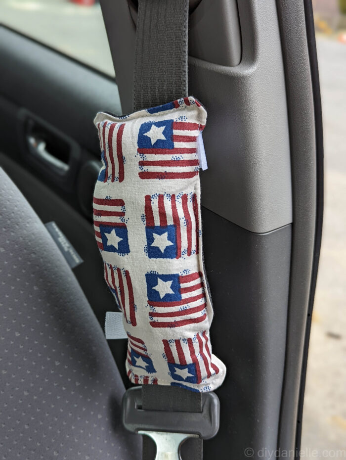 Port pillow with patriotic fabric attached to seatbelt. Please note: it's attached the wrong direction in this picture, for photographic reasons only.  The pillow will face the person in the seatbelt.