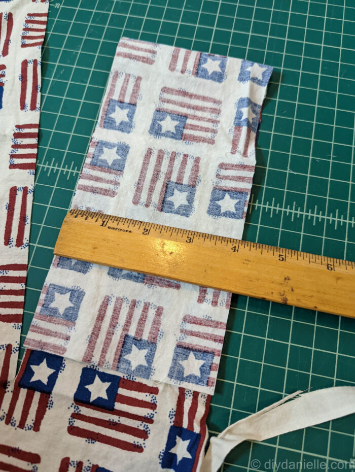 Cutting patriotic fabric for a seatbelt cushion for a chemo port. The strip of fabric is 4" wide.