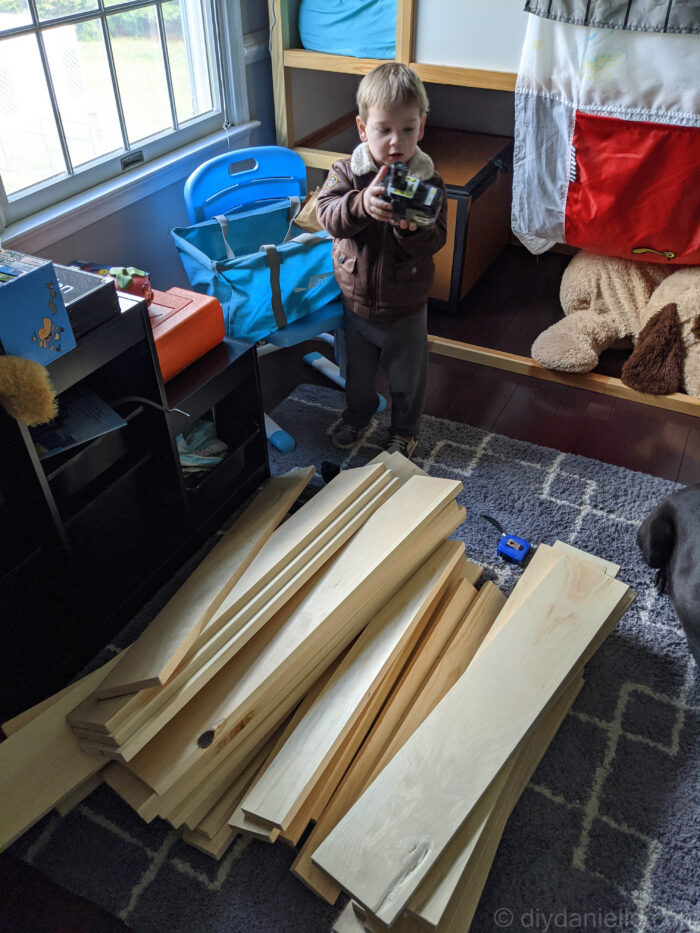 Wood cut for the toddler bed. Toddler holding a Ryobi battery.