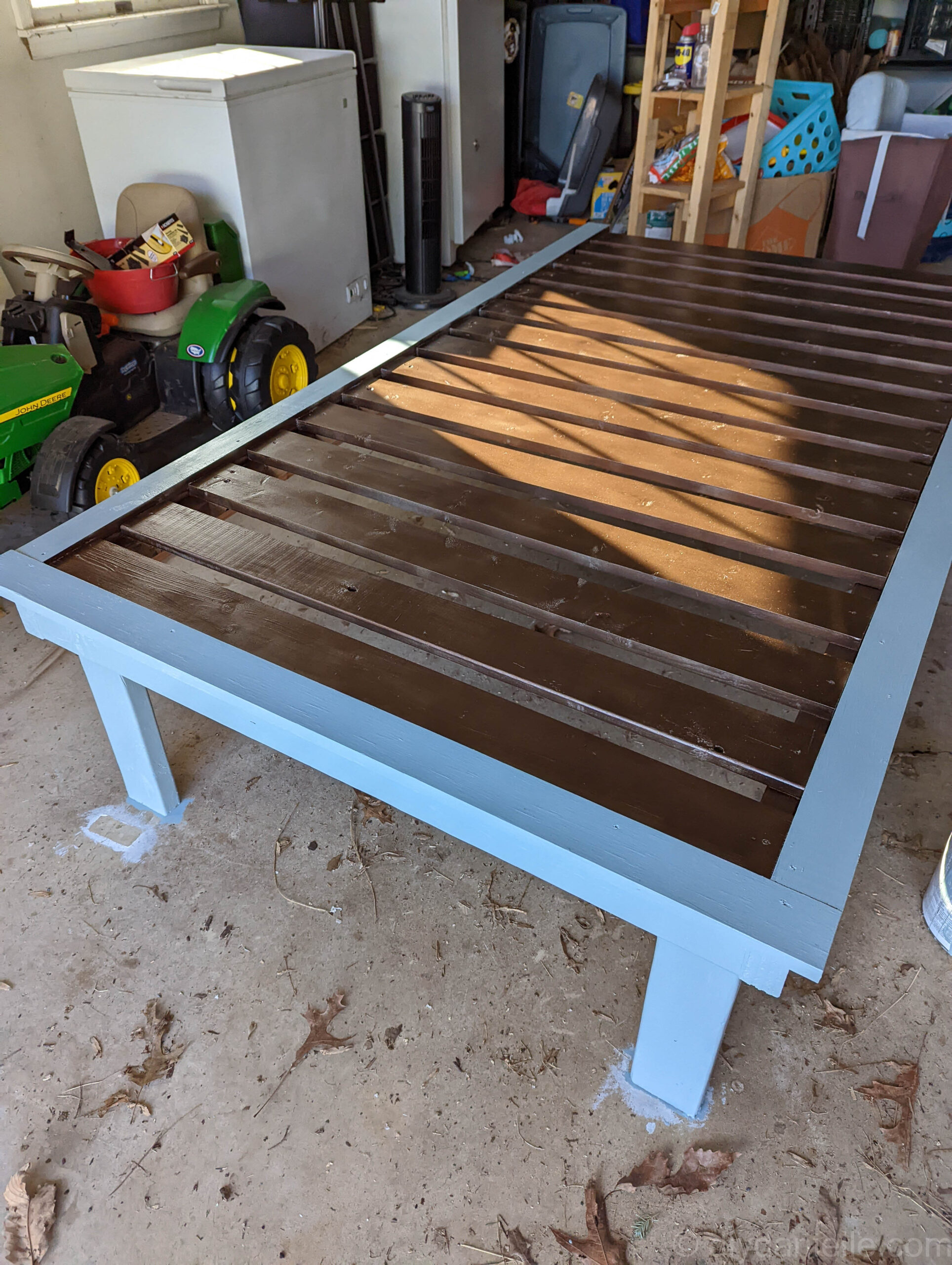 Twin bed, after it was primed and painted. It has a light blue frame and the slats are spray painted bronze. 