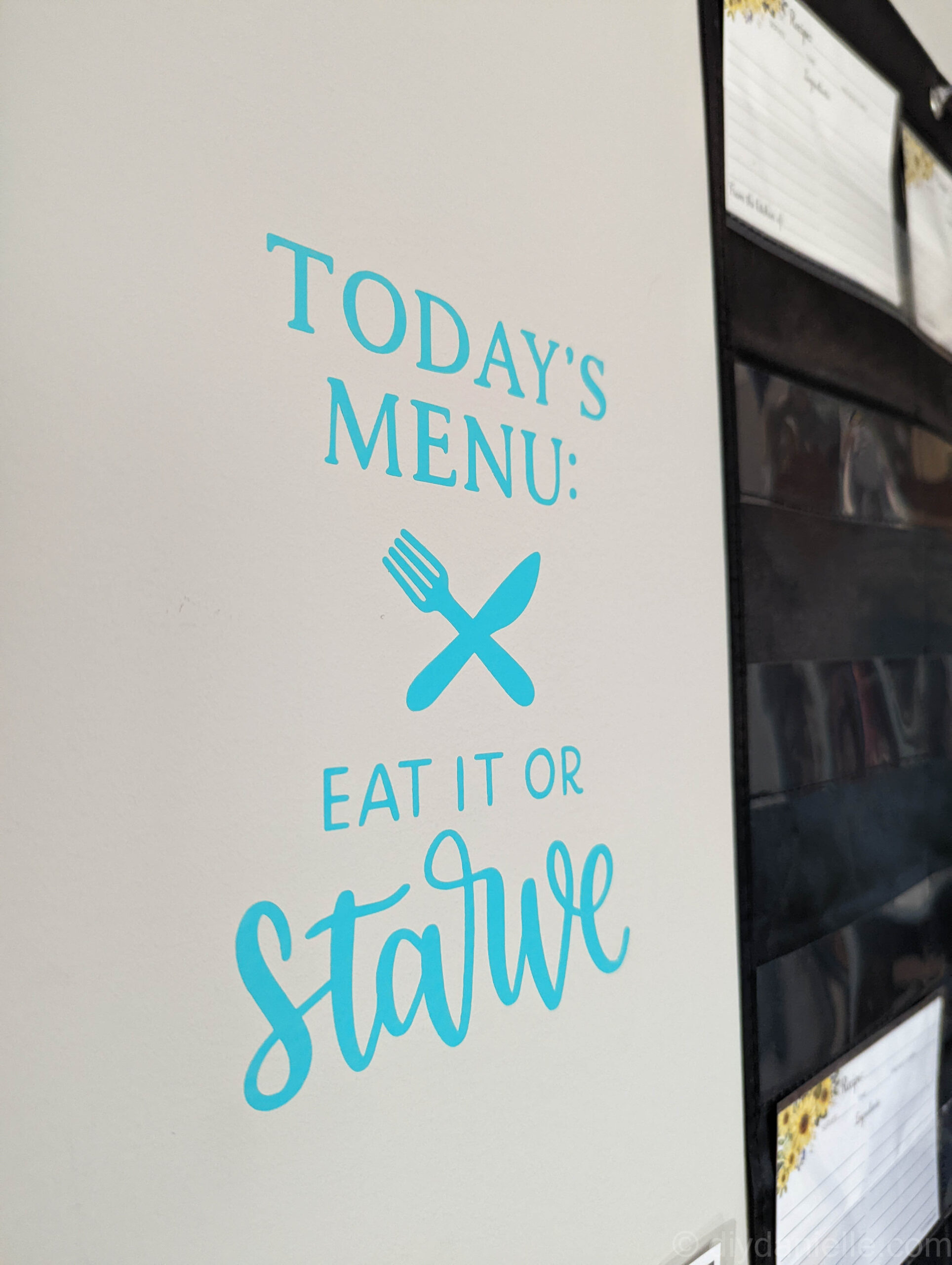 Wall decal next to my menu planner: "Today's Menu: Eat it or STARVE" with a fork and knife crossing each other. 