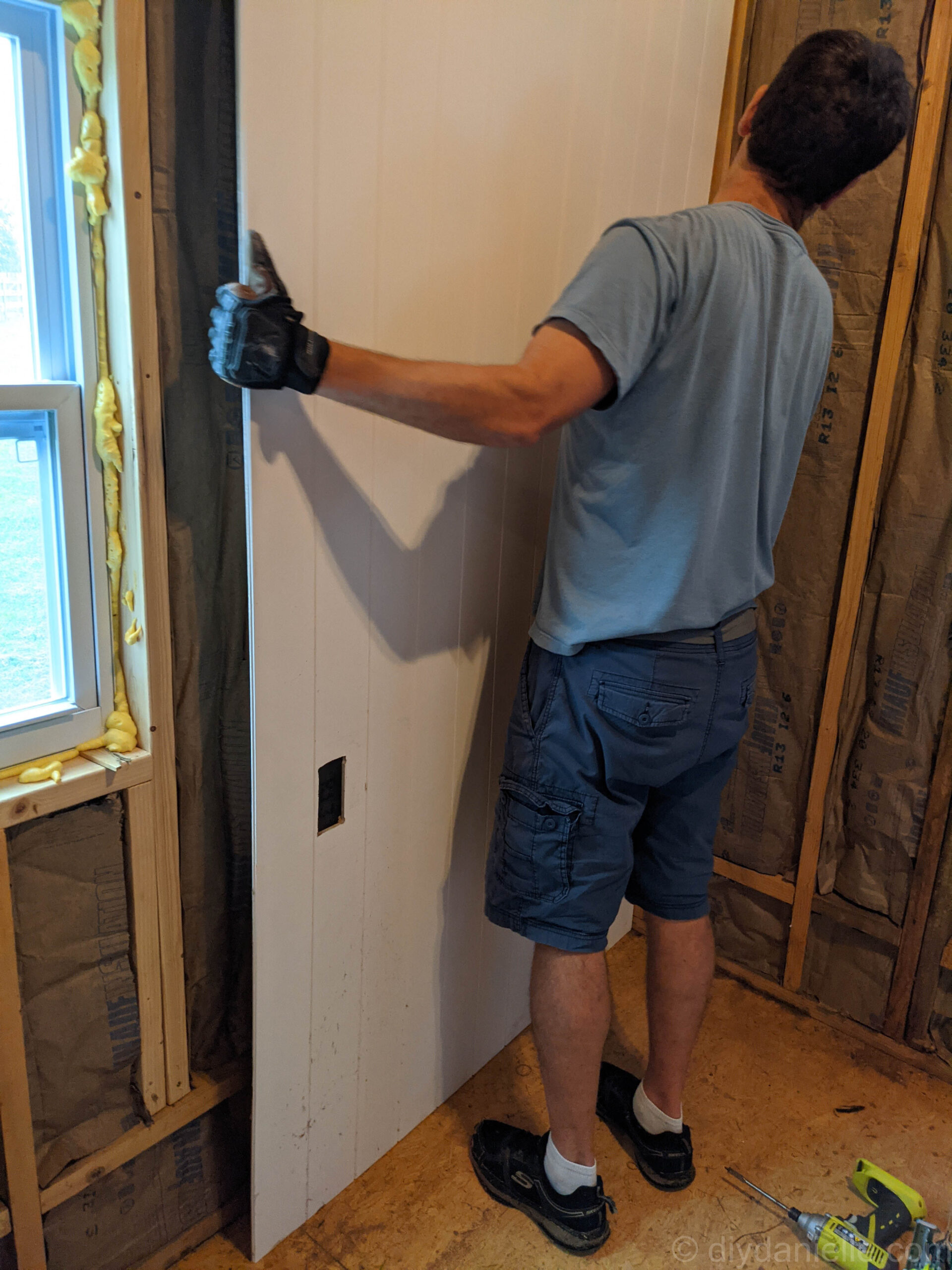 Here's my husband pushing the first panel up against the corner to make sure the cut out for the outlet is in the correct place.