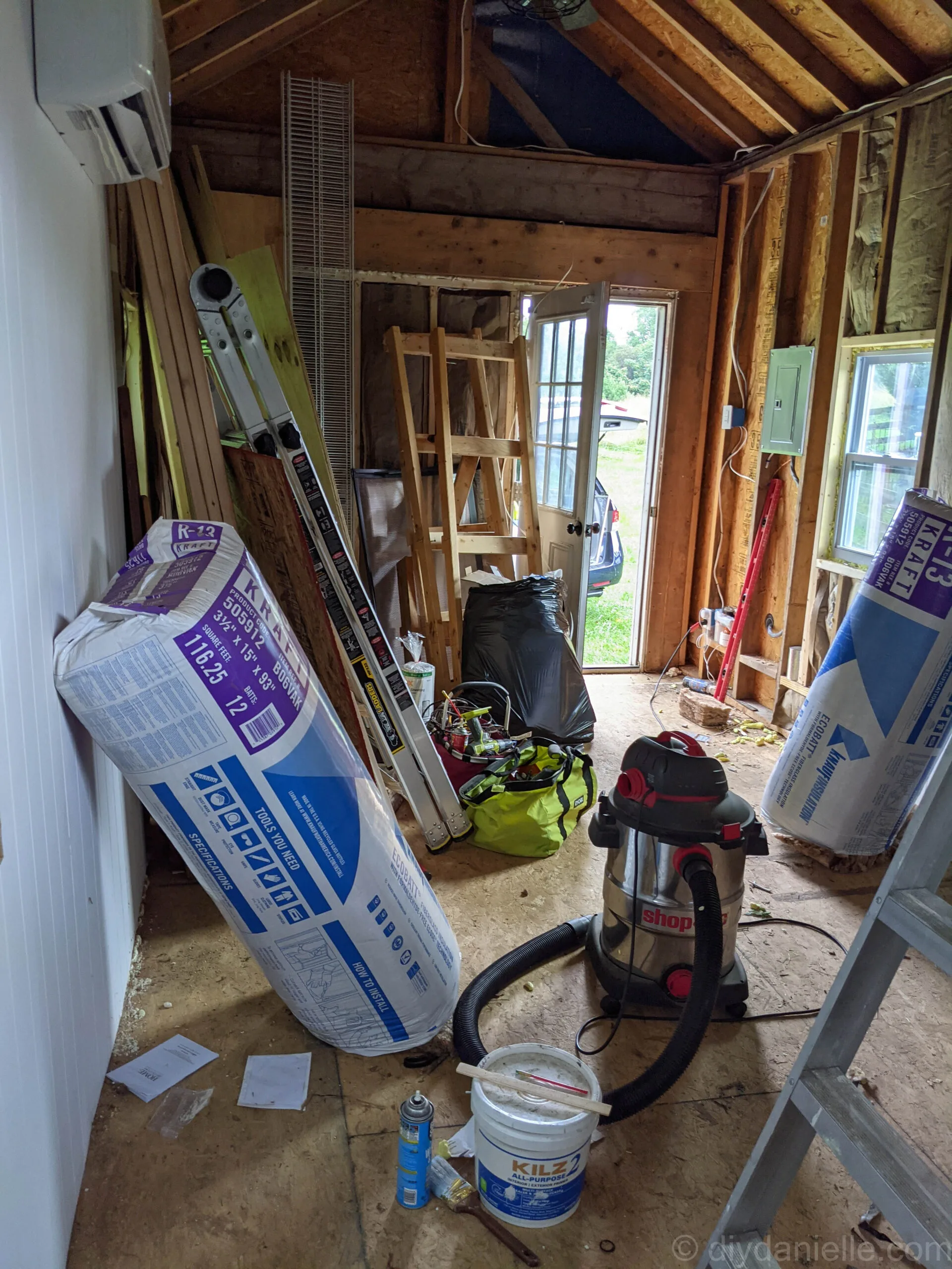 Tools and supplies laid out for vinyl plank and laminate floor installation including tapping block, spacers, mallet, measuring tape, and molding.