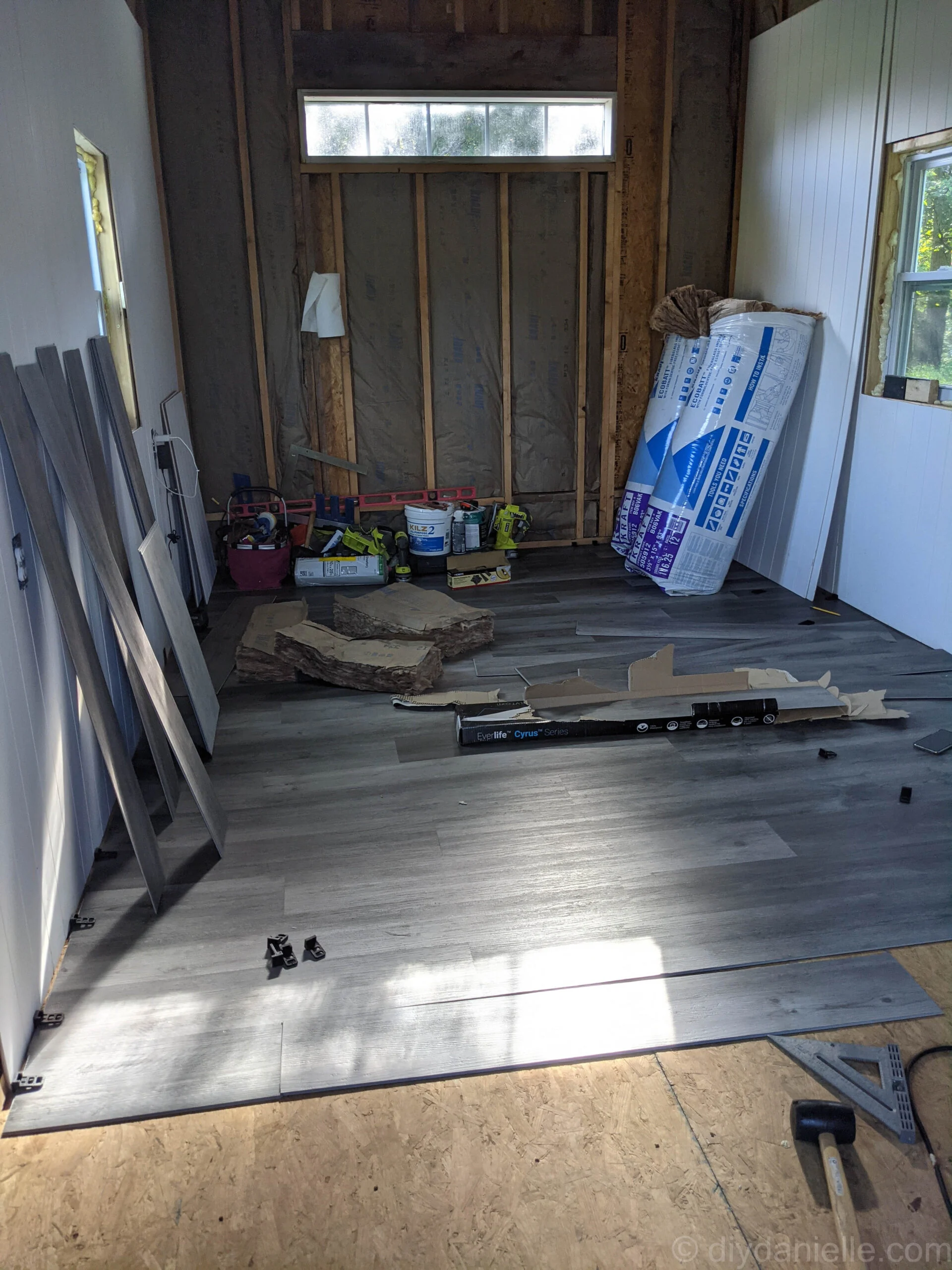 Vinyl plank flooring installation with spacers placed between planks and walls for proper spacing.