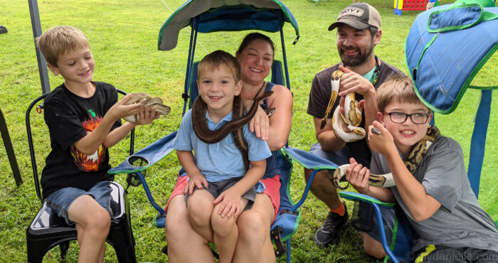 My family all holding snakes for a family photo at the reptile party!