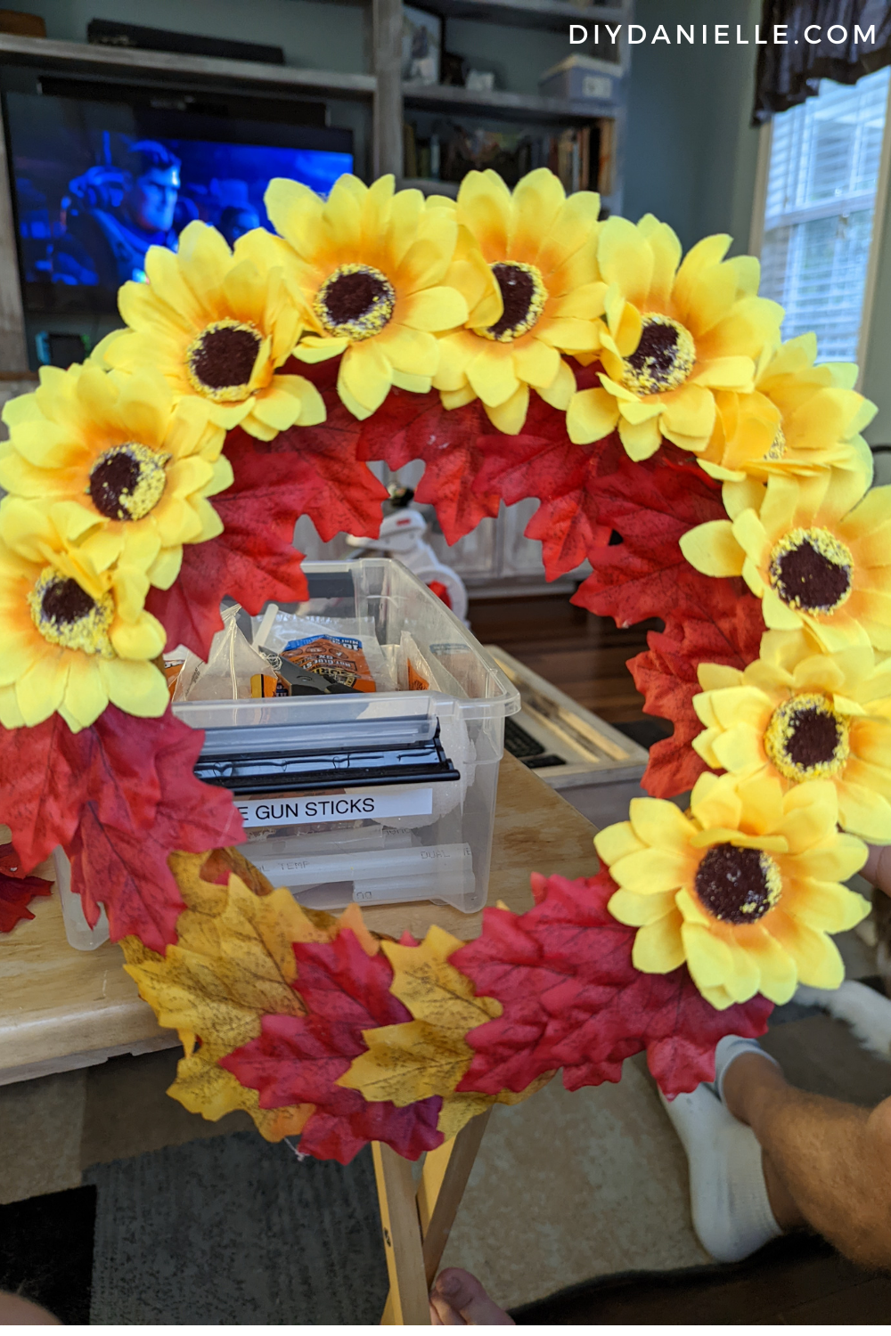 Adding sunflowers and fall leaves to a foam wreath form.