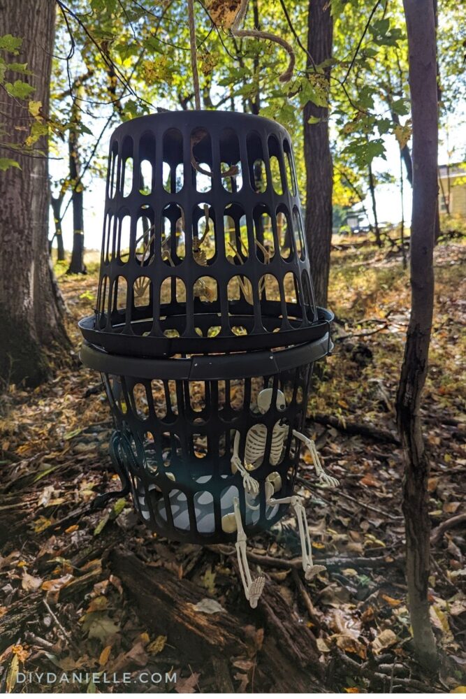 Small skeleton and skeleton bat in a cage in a tree.