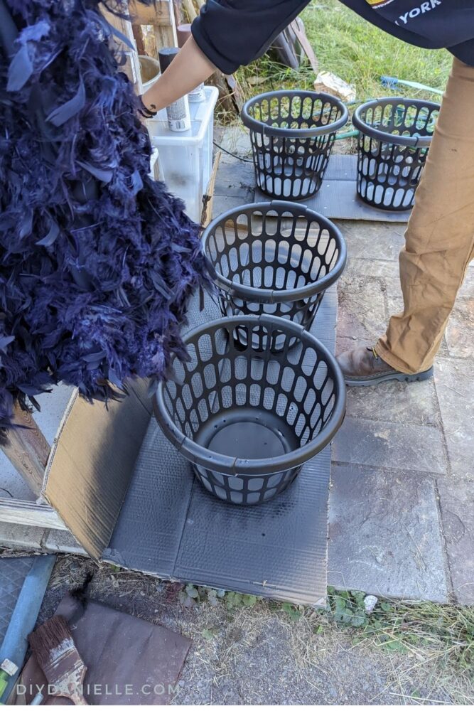 Spray painting laundry baskets black.