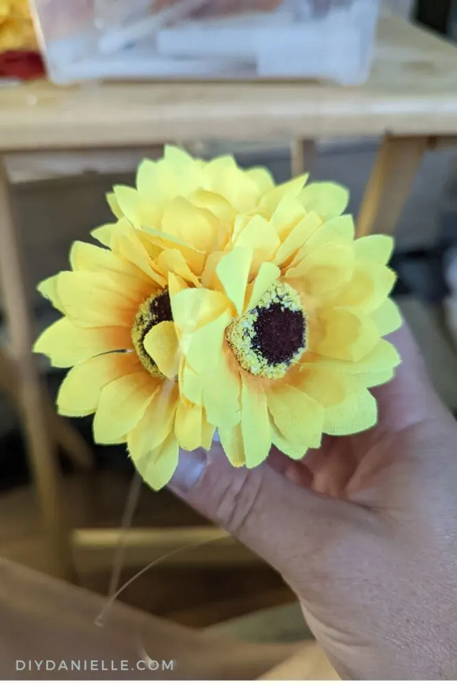 Adding artificial sunflowers to a foam craft ball.
