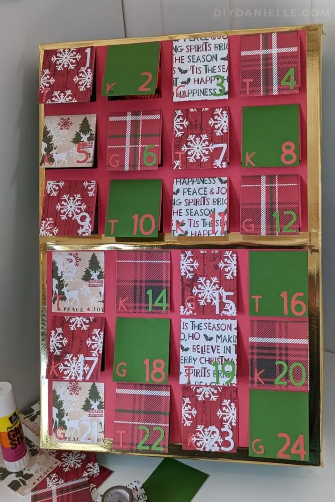 Advent Calendar made with my Cricut Maker 3, scrapbook paper, and a wood box. Initials of the child's name notate which child's turn it is to open the calendar that day.