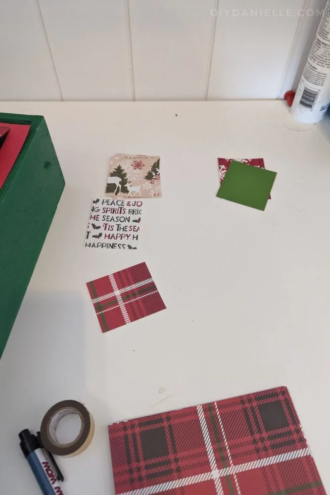 Christmas themed scrapbook paper cut out in small rectangles to go on the Advent calendar windows.