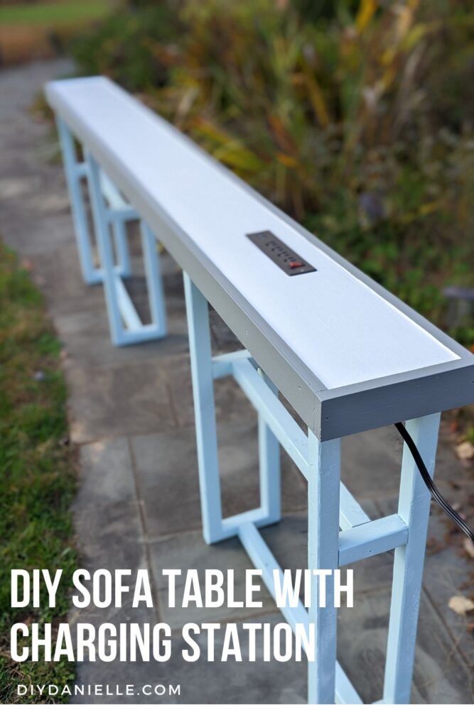 DIY Sofa Table with Charging Station. The table top is white with gray trim, there's a recessed outlet installed, and the legs of this console table are light blue.