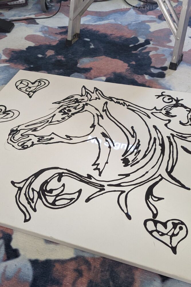 The horse head has been completely traced with black glue, and hearts were added around the horse head on the canvas.