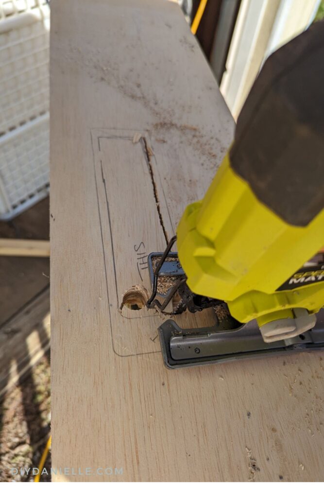 Using a jig saw to cut out the area for the recessed outlet.