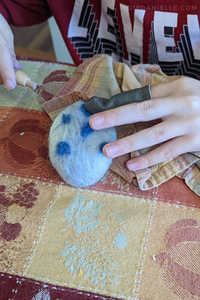 Child needle felting soap with blue dots.