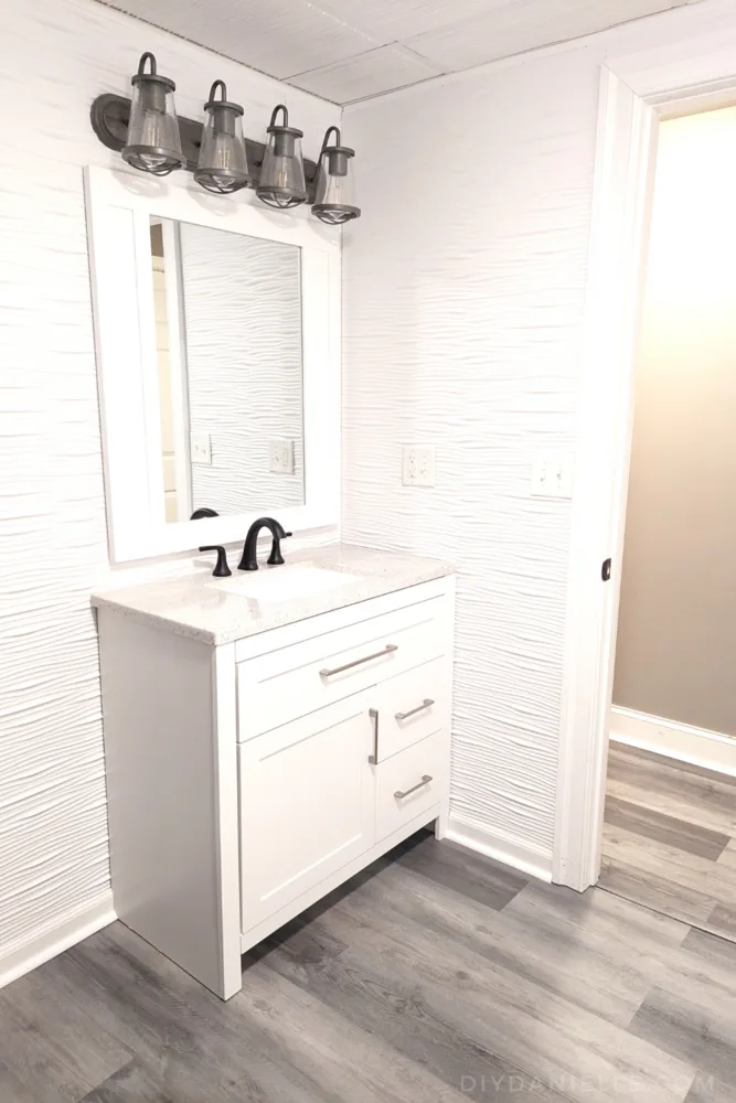 White bathroom vanity, gray flooring, and a white framed mirror. 