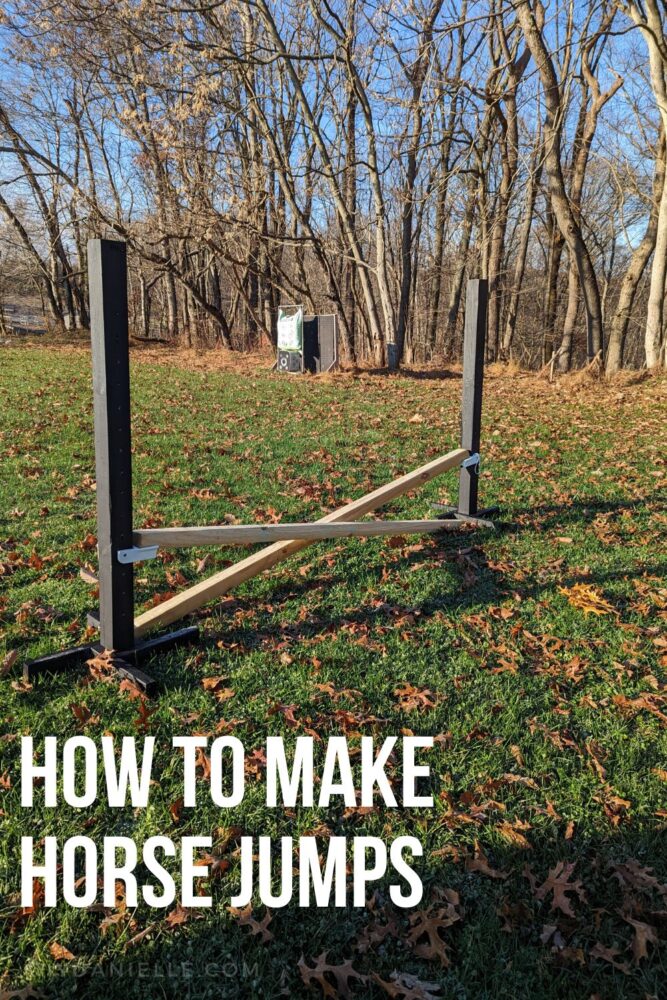 How to make horse jumps: photo of two black standards setup with cross rails made of landscape timbers.