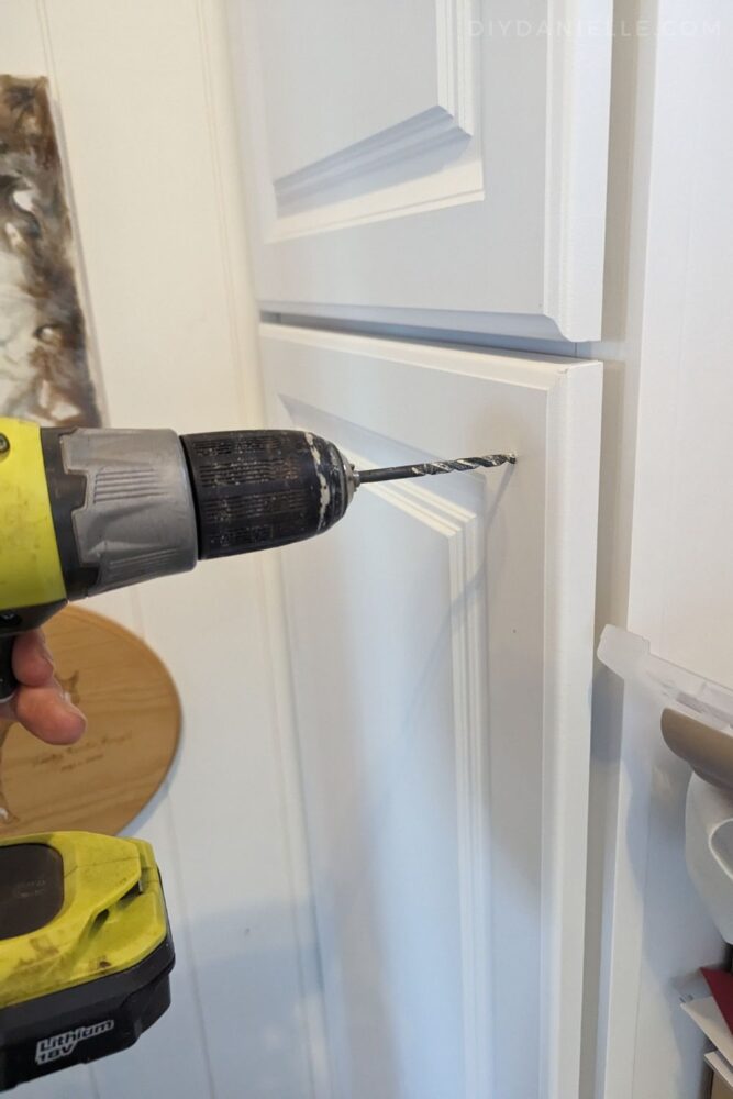 Installing cabinet handles by drilling holes for the screws. 