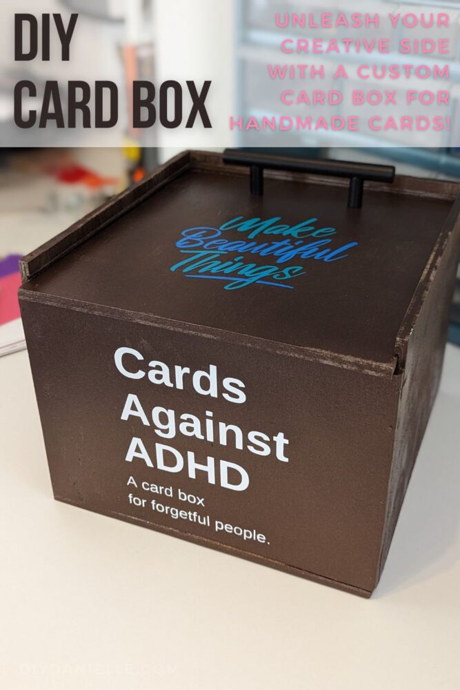 DIY Card Box painted metallic brown. The top lid has a pull attached so you can pull it and slide the lid off. The top says "Make beautiful things" in two tones of blue permanent Cricut vinyl. The front of the box says "Cards against ADHD: A card box for forgetful people."