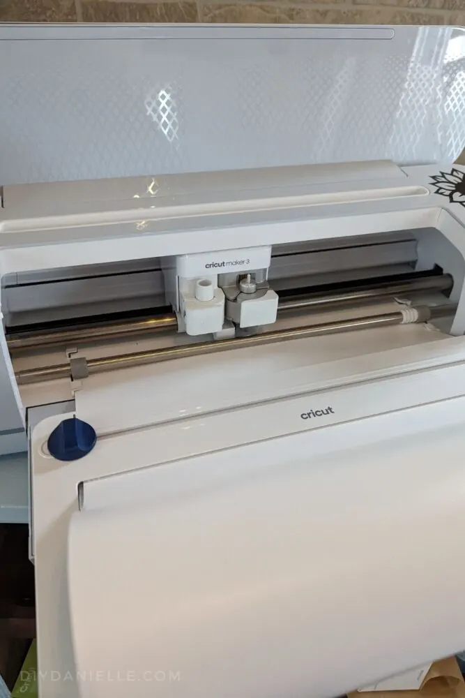 White roll of Cricut Smart Vinyl loaded into the Cricut Maker 3 with the roll holder.