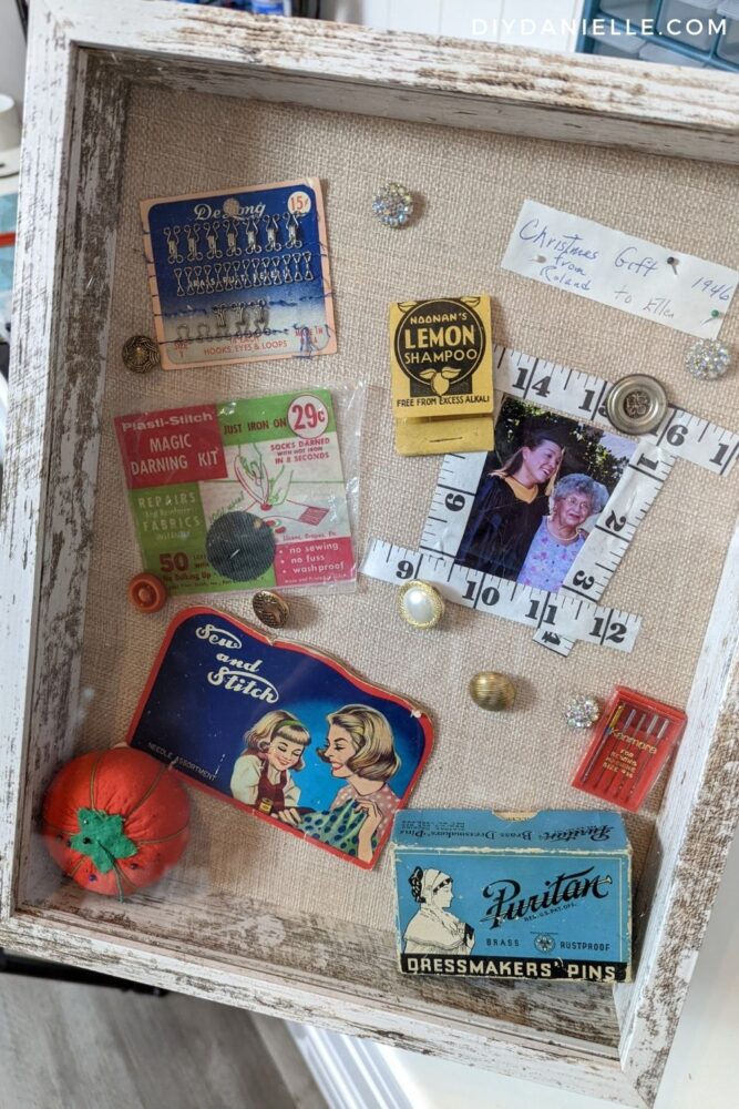 Sewing Shadow Box made with 1946 sewing supplies. Photo of my grandma and I framed with a cut up measuring tape. 29 cent darning kit. Sew and Stitch kit. Antique buttons. Puritan Dressmakers Pins