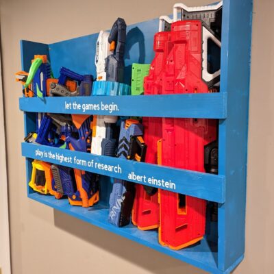 Nerf gun storage rack on the wall, full of Nerf guns and bows.