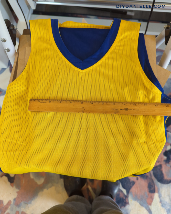 Plain basketball jersey being measured to determine the maximum width for the names and numbers.